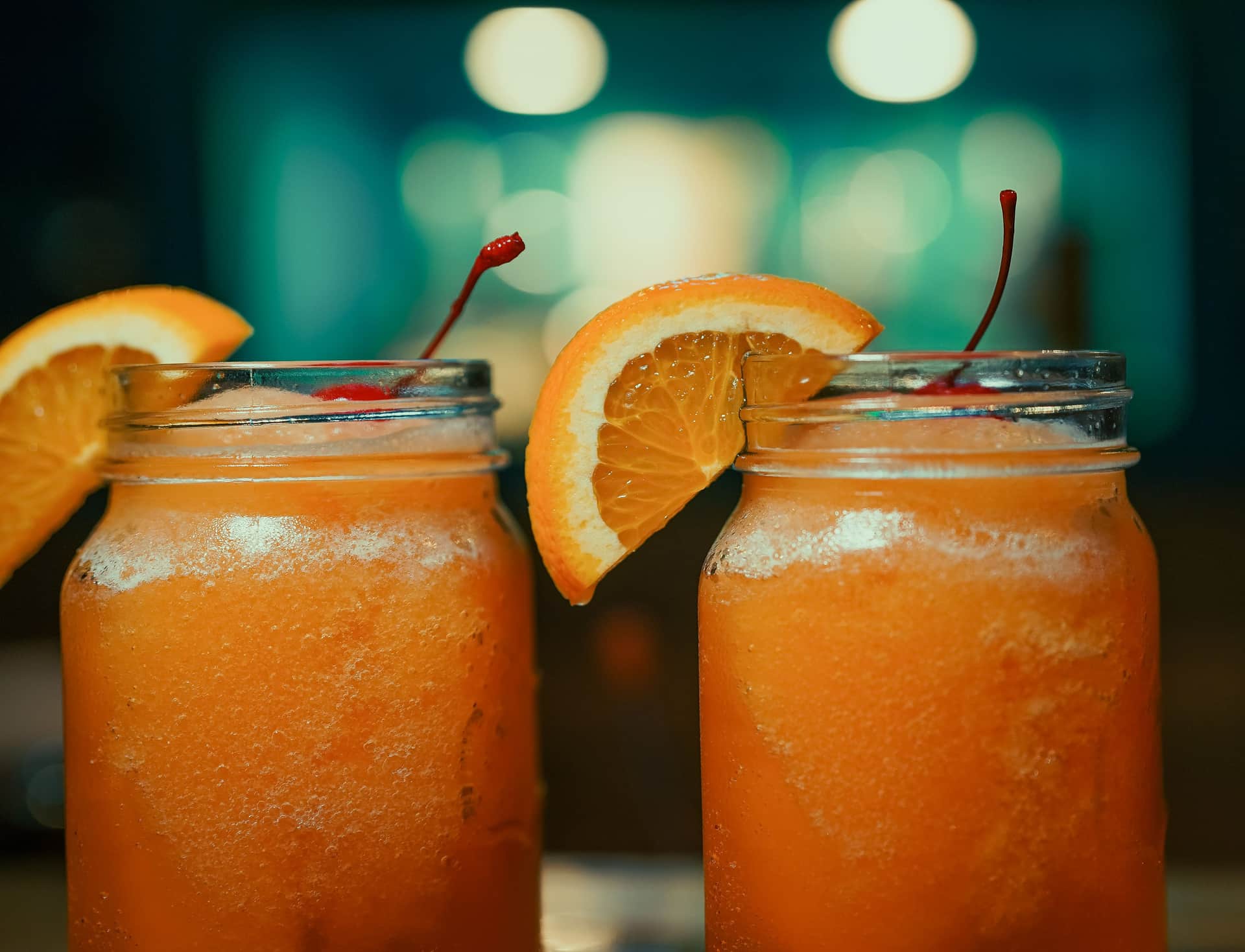 Two glasses of iced drinks side by side on a counter