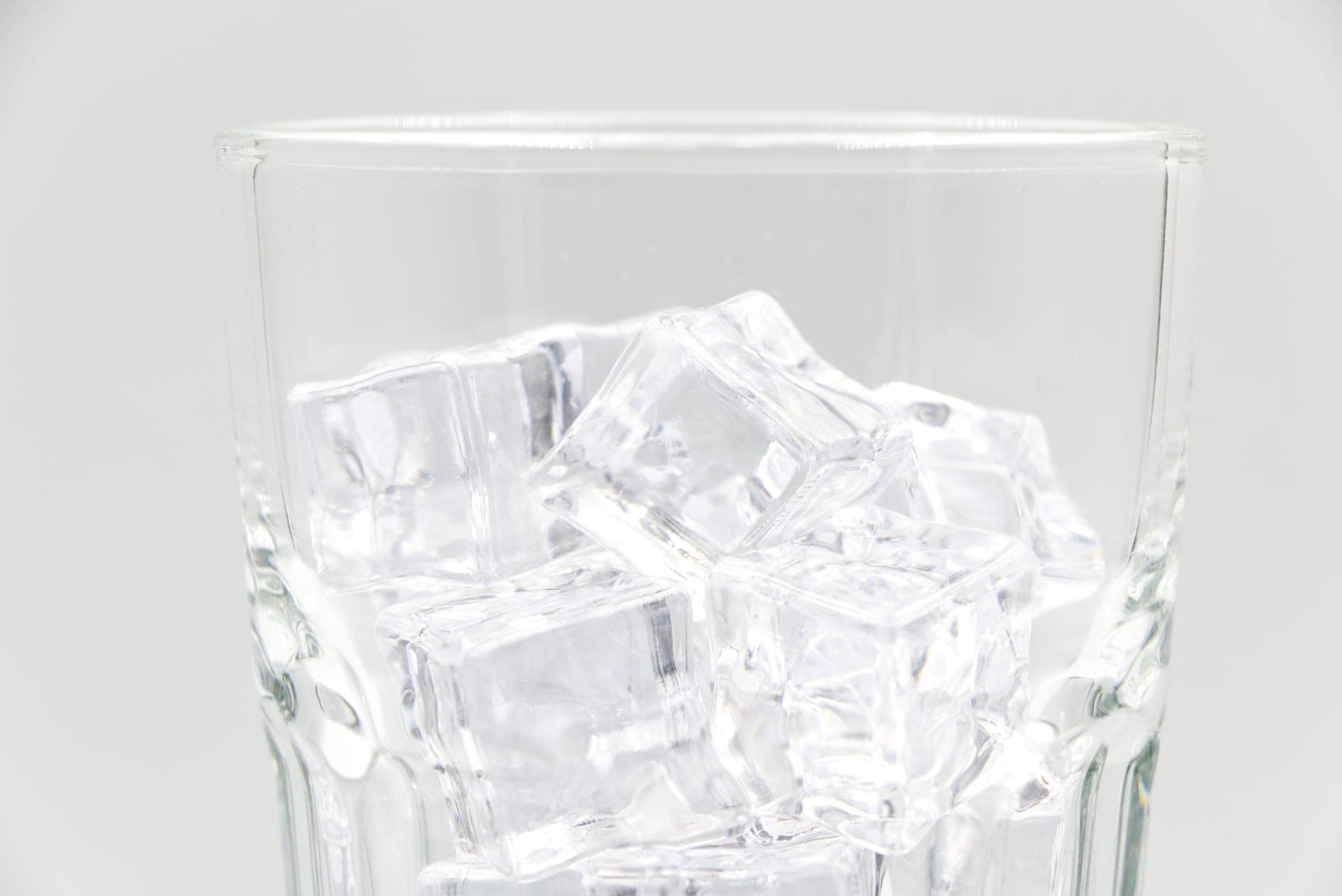 Hard bullet-shaped ice cubes falling into a glass
